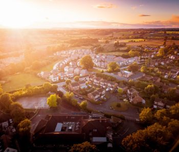 Sun rising above a traditional British housing estate with countryside in the background.