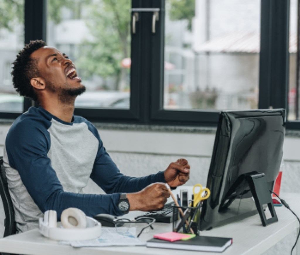 angry african american programmer gesturing while sitting at workplace in office