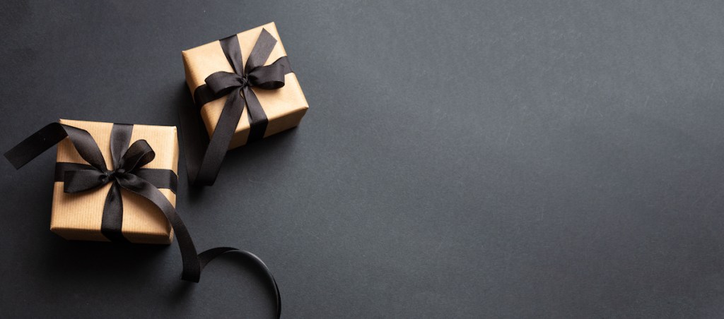 Gifts with black ribbon against black background, Black Friday concept.