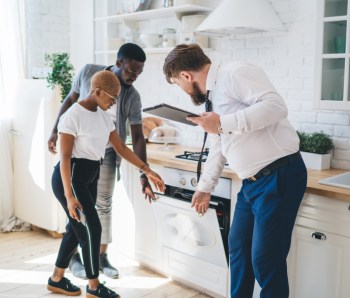 Confident estate agent showing kitchen to African American thoughtful couple