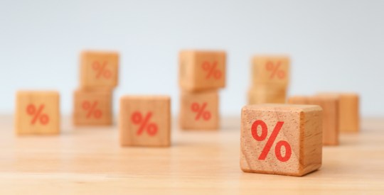 Interest rate financial and mortgage rates concept. Hand choosen wooden cube block with icon percentage symbol